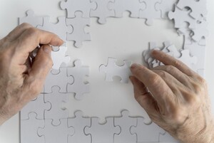 Zwei Hände setzen ein Puzzle zusammen.