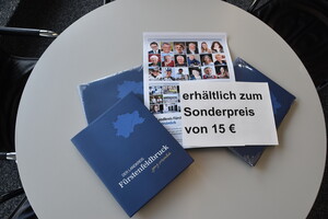 Landkreisbuch, Preisschild und Plaket liegen auf einem grauen Tisch.