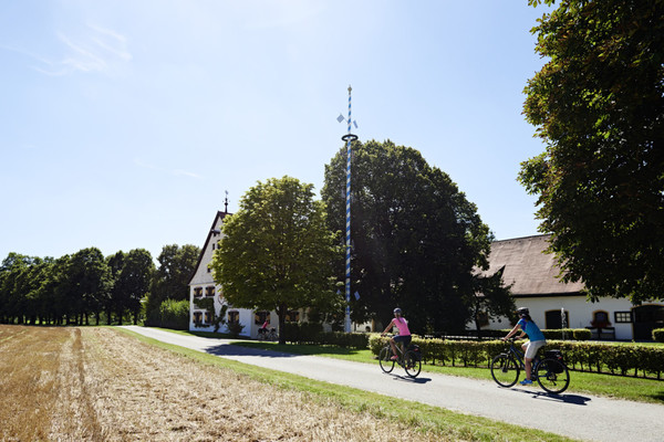 Zwei Fahrradfahrer vor dem Zellhof mit Maibaum