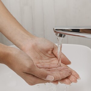 Hände unter Wasserhahn.
