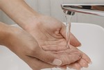 Hände unter Wasserhahn.