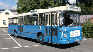 Historischer blauer Bus steht auf Parkplatz.