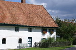 Seitenansicht eines alten Bauernhauses mit Schrebergarten.