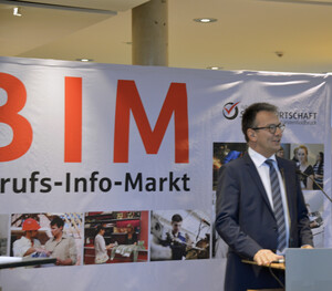 Landrat Thomas Karmasin am Rednerpult. Im Hintergrund ein Banner des Beruf-Info-Marktes.