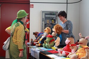 Clown steht vor einem Tisch mit Handpuppen.