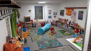Zimmer voller Spielzeug, u.a. Stofftieren, eine Textilröhre zum Krabbeln, eine Tafel.