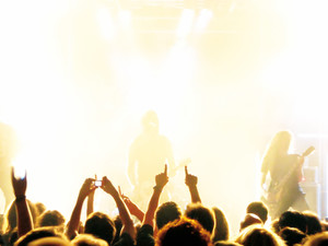 Foto: Jugendliche vor Konzertbühne, die Hände nach oben strecken.
