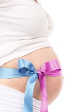 Foto: Unbekleideter Bauch einer Schwangeren mit einer Geschenkschleife