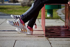 Foto: Füße zweier Jugendlicher, die auf Bank sitzen