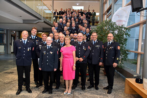 Gruppenfoto. Rund 60 Personen in Feuerwehranzügen auf einer Treppe versammeltuf eine Treppe