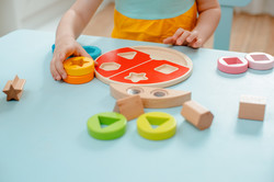 Symbolfoto: Kind am Tisch, das mit Holzspielzeug spielt.