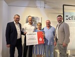 Personen halten großen Spendenscheck hoch.