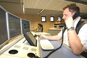 Foto zeigt telefonierenden Disponentn am Schreibtisch, der vor 4 Bildschirmen sitzt.